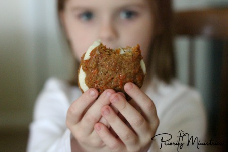 Girl eating a carrot spice sandwich cookie for thanksgiving dessert.